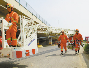 两名消防战士抬着破拆工具跑向登高车。